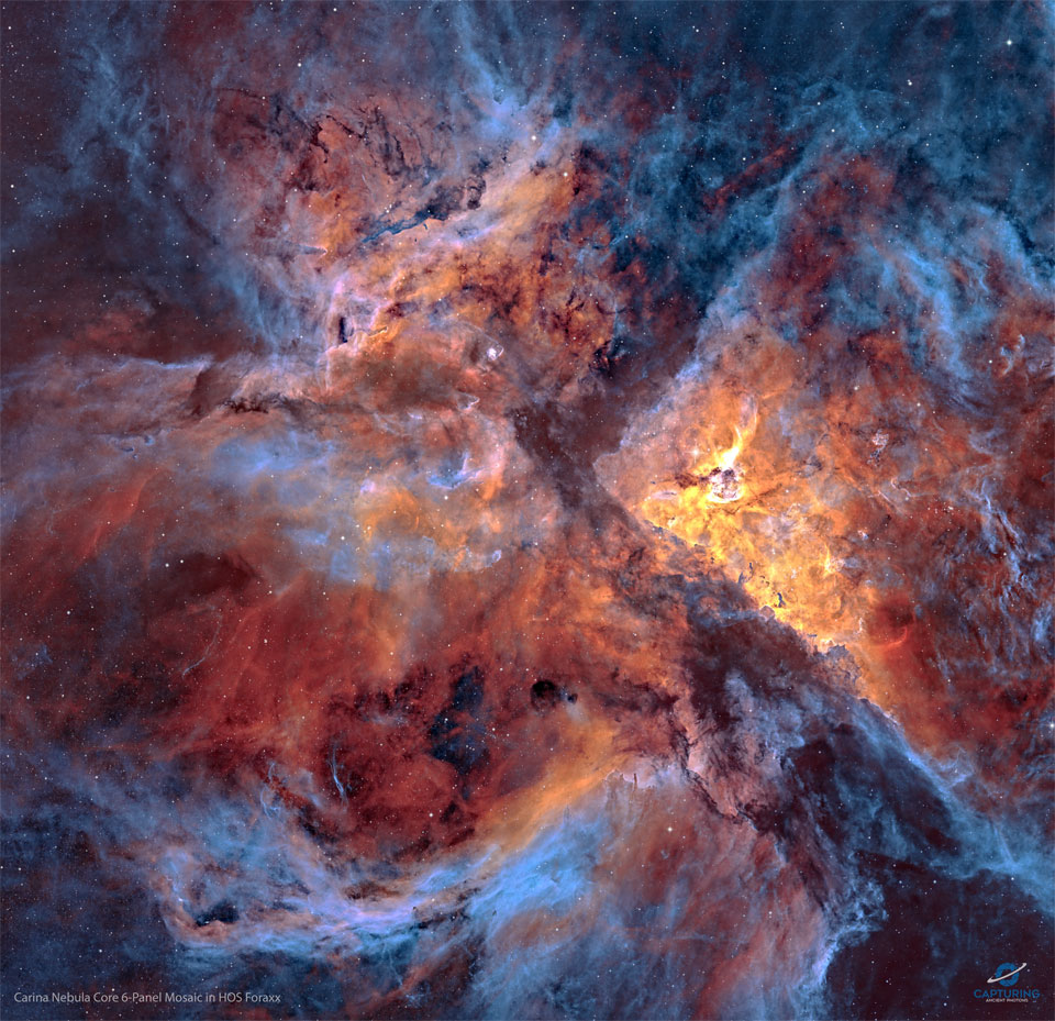 A star field strewn with filaments of dust and gas
is shown: the center of the Carina Nebula. Shown in 
colors emitted by specific elements, the frame shows
blue gas around the edges and orange and red colored
gas in the center. Dark dust laces the busy frame. 
Please see the explanation for more detailed information.