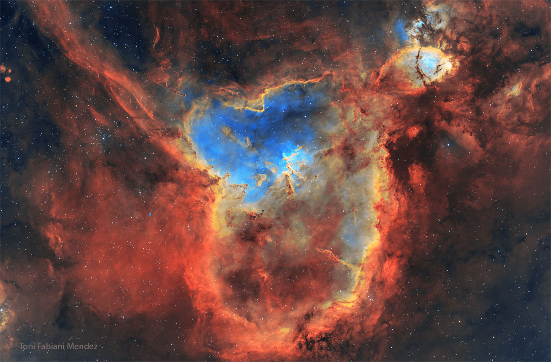 A starfield is shown filled with colorful gas glowing
in different colors, and dark dust.
Please see the explanation for more detailed information.