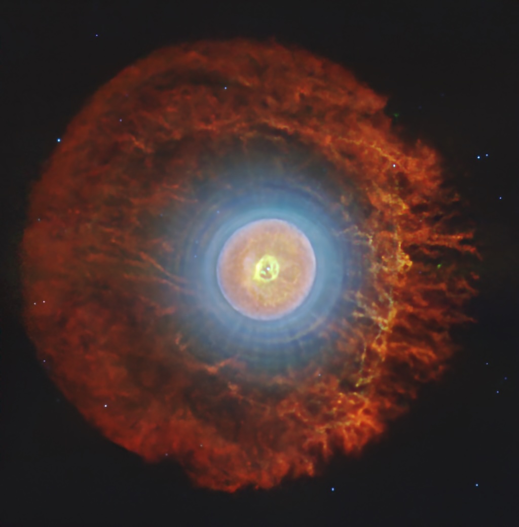 A spherical nebula shows concentric
	  rings of different colors over a dark
	  background with a few stars.