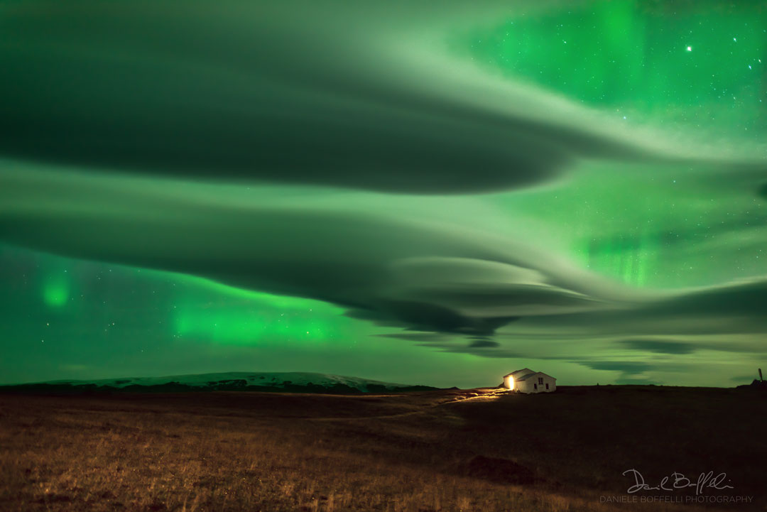 The picture shows green aurora through odd lenticular clouds.