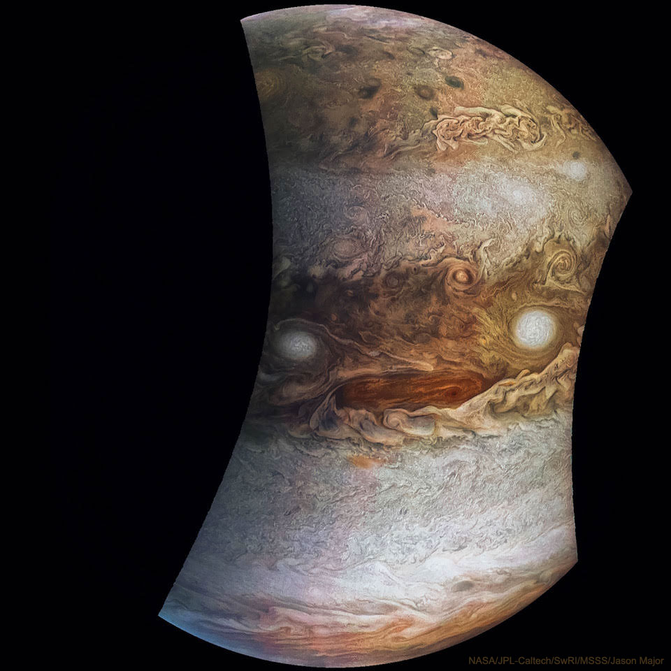 La imagen muestra a Júpiter durante un paso de Juno en un momento en que algunas de las nubes parecen una cara.  Consulte la explicación para obtener información más detallada.