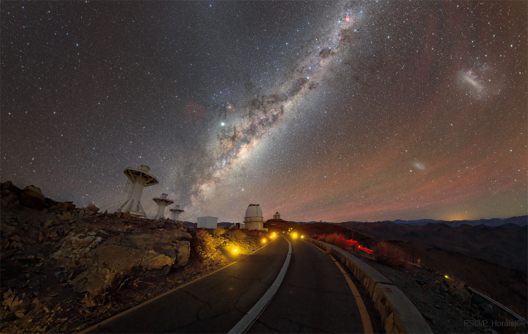An image of the road to the La Silla Observatory in Chile with
telescope on the horizon and stars, galaxies, planets, and airglow
in the sky.
Please see the explanation for more detailed information.
