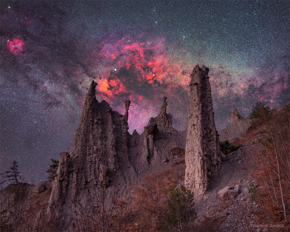 La imagen destacada muestra una colina en los Alpes franceses con agujas de roca conocidas como hoodoos.  En el fondo está la galaxia de la Vía Láctea completa con estrellas brillantes, nubes de polvo oscuro y nebulosas rojas.  Consulte la explicación para obtener información más detallada.