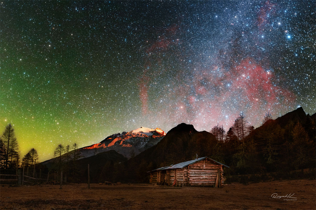 The featured image shows expansive Gum Nebula,  glowing in red, behind a landscape with a wooden hut   and snowy mountains.   the unusual light  Please see the explanation for more detailed information.