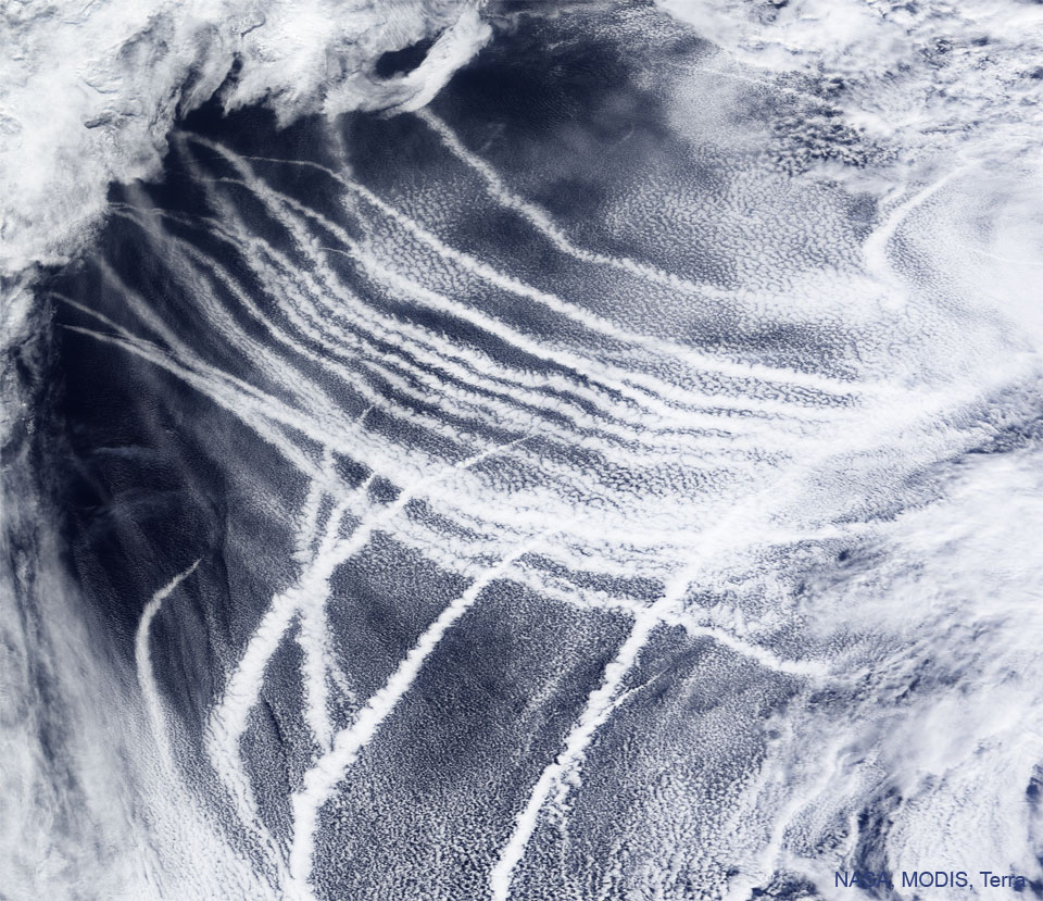 La imagen destacada rastrea el barco sobre el Océano Pacífico según lo capturado por el instrumento MODIS en el satélite Terra de la NASA.  Las huellas aparecen como rayas blancas sobre el océano azul.  Consulte la explicación para obtener información más detallada.