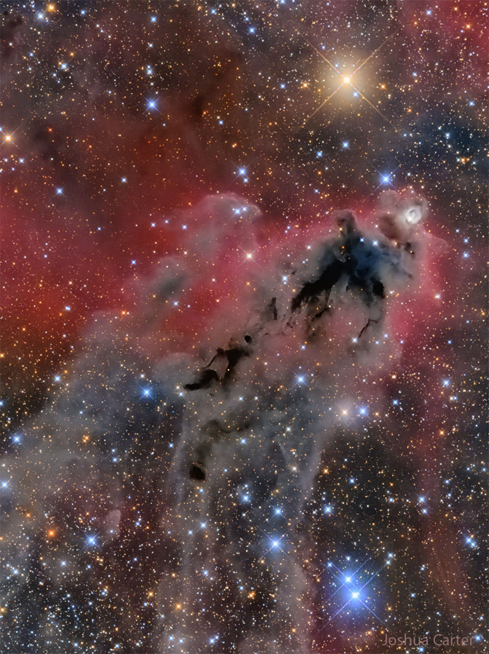 An image of a foreboding dark nebula before a red-glowing gas   background and many bright and colorful stars.  Please see the explanation for more detailed information.