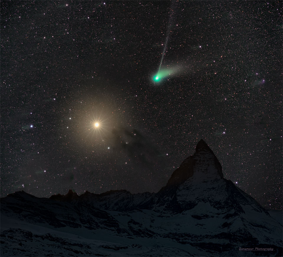 A deep starfield features an orange planet Mars on the left
and a green-headed Comet ZTF on the right. In the foreground
is a landscape that includes the top of a famous mountain 
known as the Matterhorn.
Please see the explanation for more detailed information.