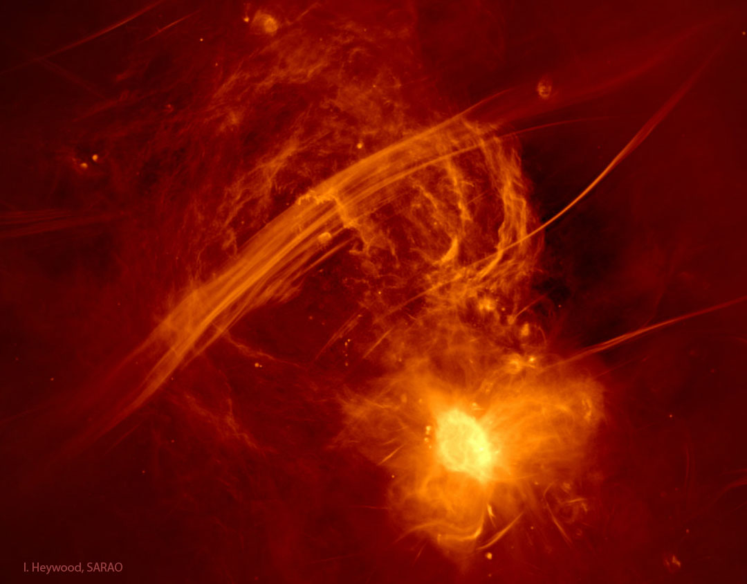 A false-color yellow-on red radio image of our
Galactic Center shows yellow radio-emitting arcs above streaks and a
bright cocoon that contains our Galaxy's central
black hole.
Please see the explanation for more detailed information.