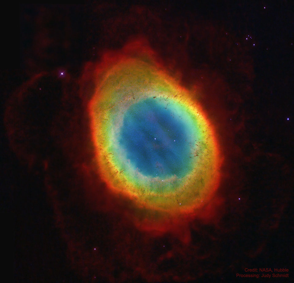 A colorful oval nebula is shown star field is shown 
in a sparse starfield. Fainter red nebulosity surrounds the
bright oval. A relatively bright star is seen in the oval's
center.
Please see the explanation for more detailed information.