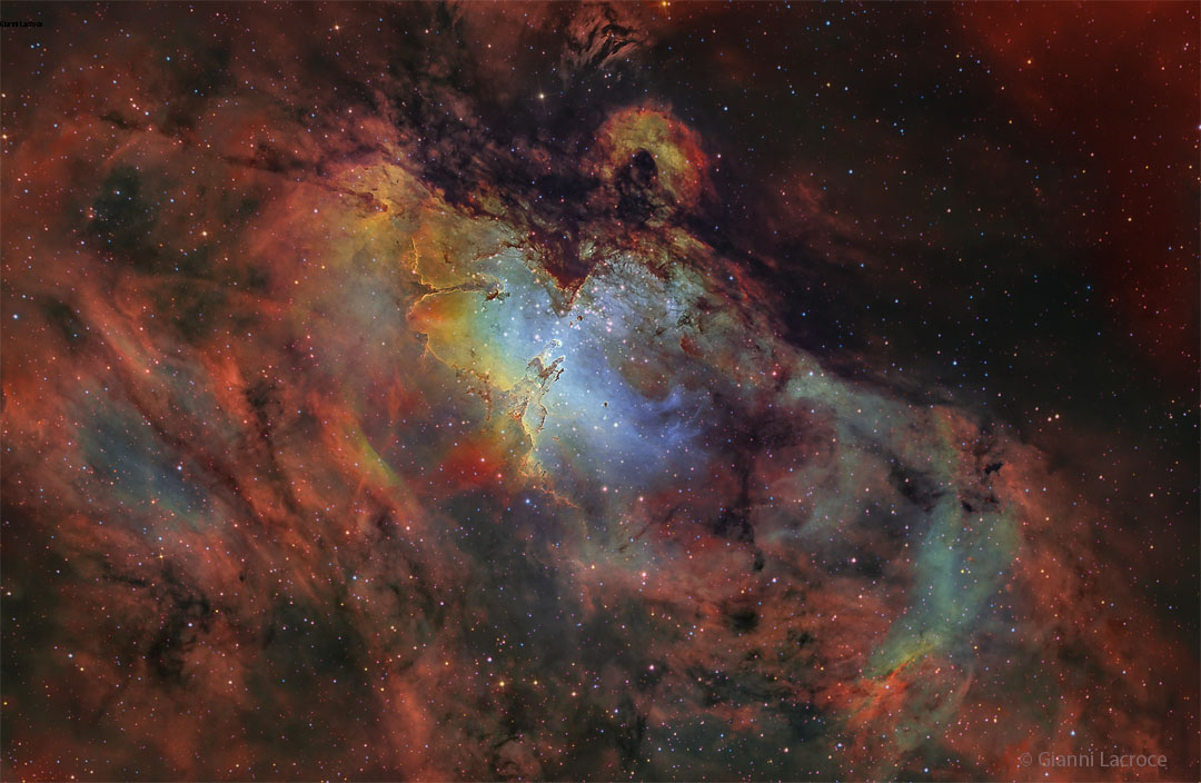 A deep image of the Eagle Nebula in many scientifically
assigned colors. The area around the nebula appears red, but 
the center is blue with unusual pillars visible. 
Please see the explanation for more detailed information.