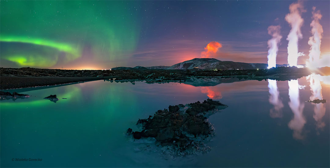 A body of water is seen in front of a night sky. The
water reflects the sky. In the sky, on the right are green
aurora. In the center is an orange plume. On the right
are three while plumes. 
Please see the explanation for more detailed information.