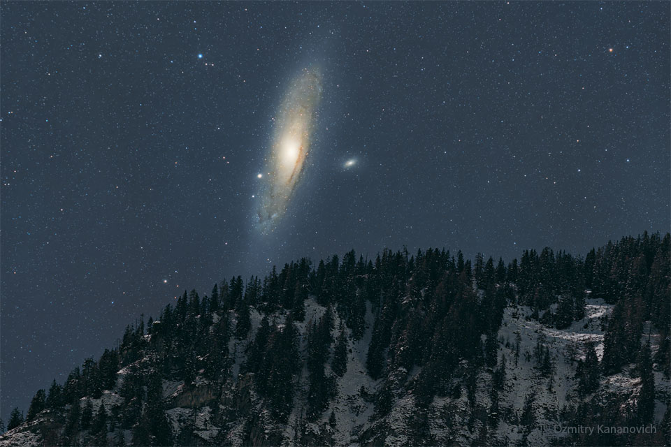 The night sky over a snowy mountain is shown, with the  dark sky dominated by a large spiral galaxy -- the Andromeda  galaxy.  Please see the explanation for more detailed information.