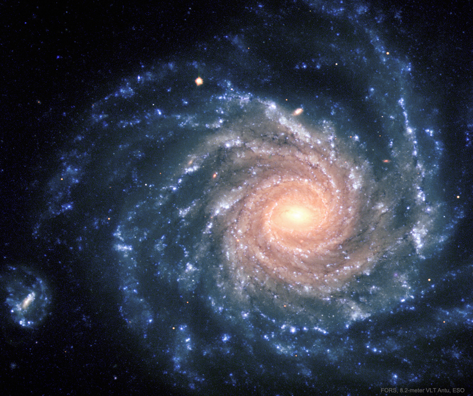 A spiral galaxy with big blue spiral arms is shown with
 a center that appears more yellow.
Please see the explanation for more detailed information.