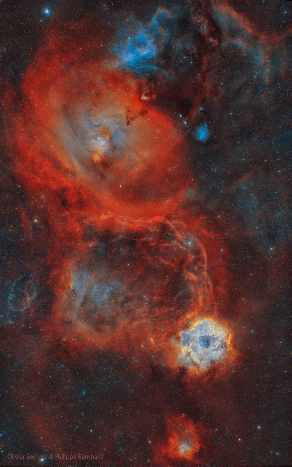 A busy star field is shown with several large red
nebulae. The Rosette Nebula is among them and seen on 
the lower right, while the nebula surrounding the 
Cone Nebula is larger and visible toward the upper left.
Please see the explanation for more detailed information.