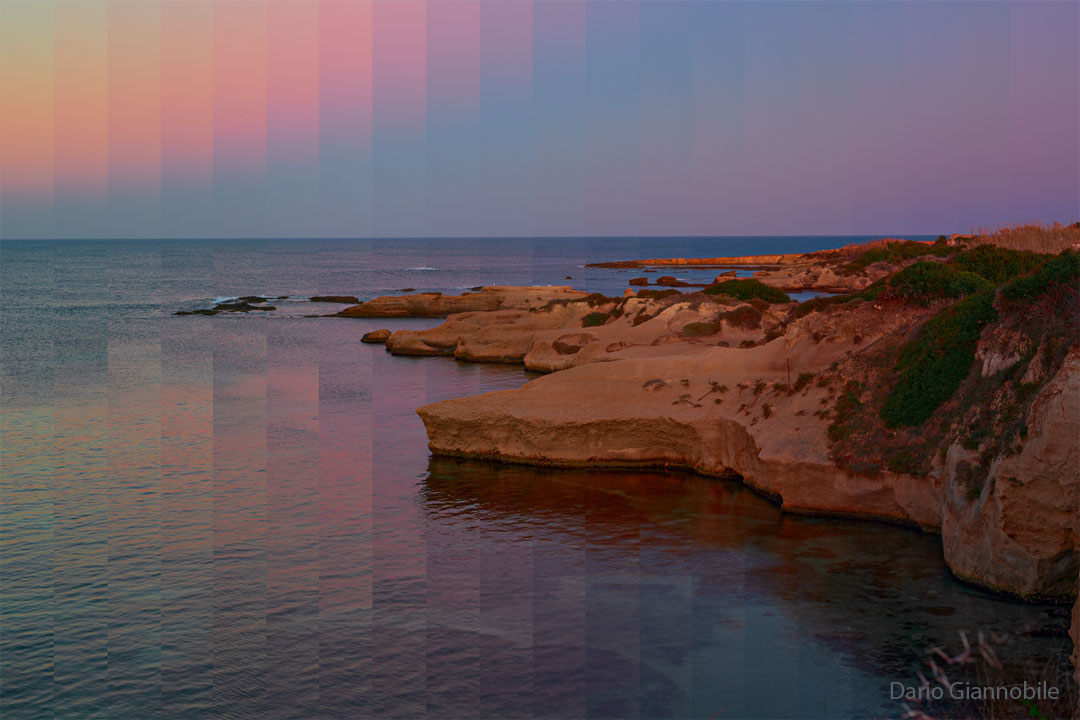 A rocky shoreline is shown with land on the right and water 
on the left. Above is a sky that shows unusually pixelated and colored
vertical bands.  
Please see the explanation for more detailed information.
