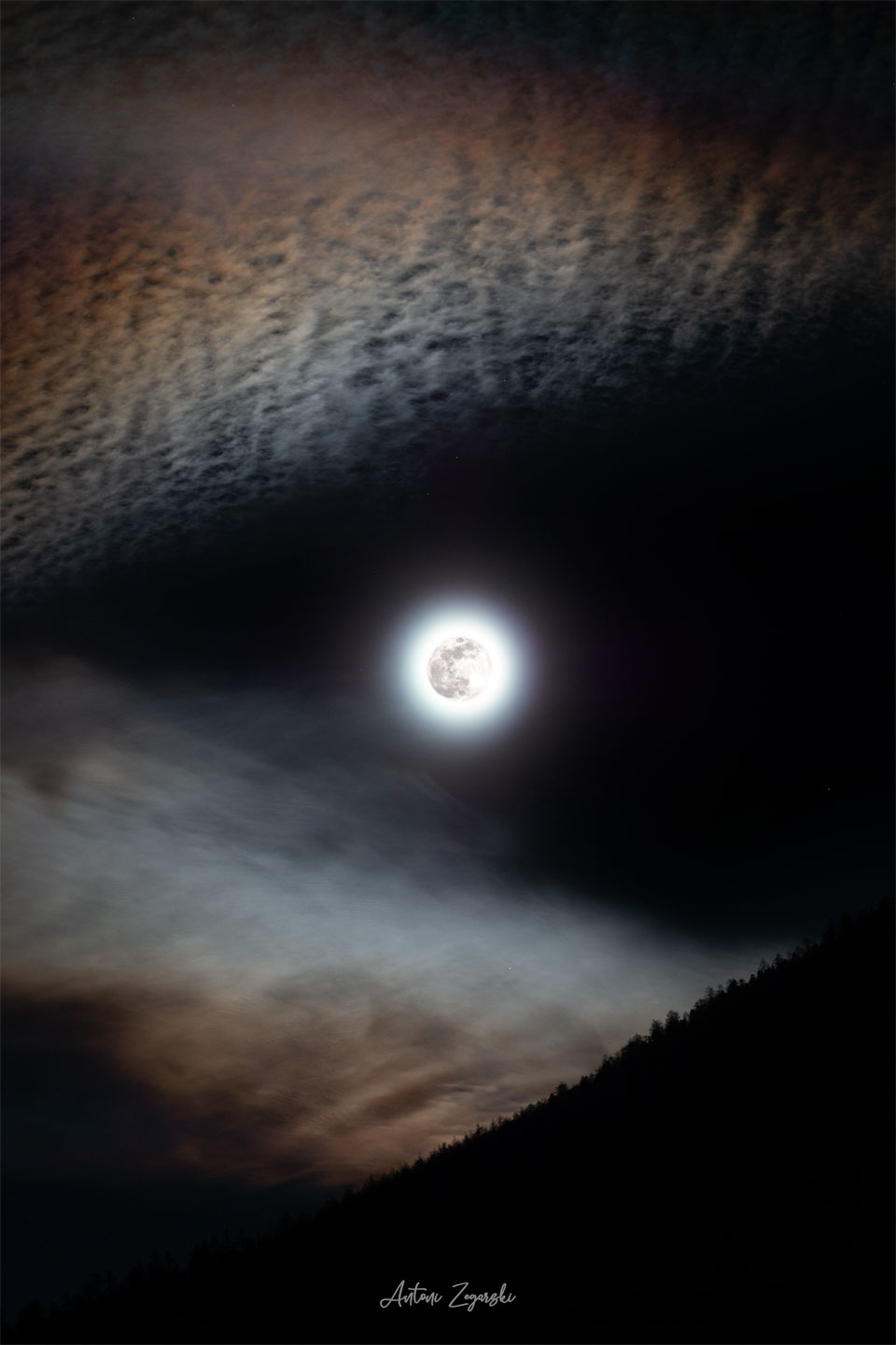 A bright full moon is seen in the center of the
image. Angular clouds are seen around the edges which
make the moon look like it is either in the mouth
of the wolf, or the eye of a wolf. 
Please see the explanation for more detailed information.