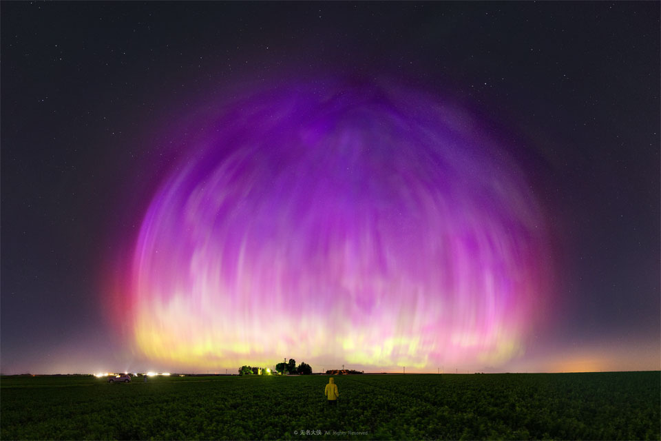 
A large purple transparent dome appears to cover much of a starry
sky. A person stands in a field looking toward the unusual spectacle.
Please see the explanation for more detailed information.