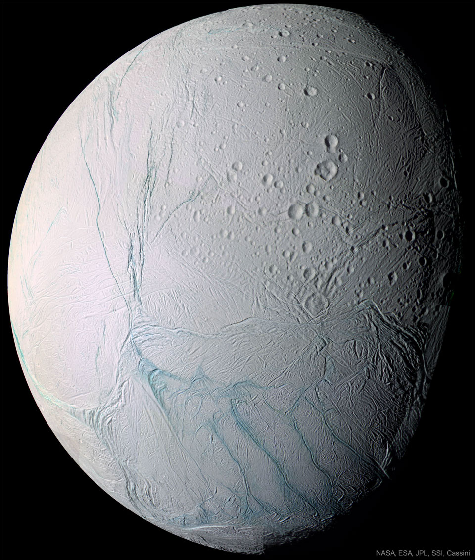 A light-colored spherical body is shown mostly illuminated
against a dark background. Many craters are visible. Unusual
blue stripes meander on the surface. 
Please see the explanation for more detailed information.