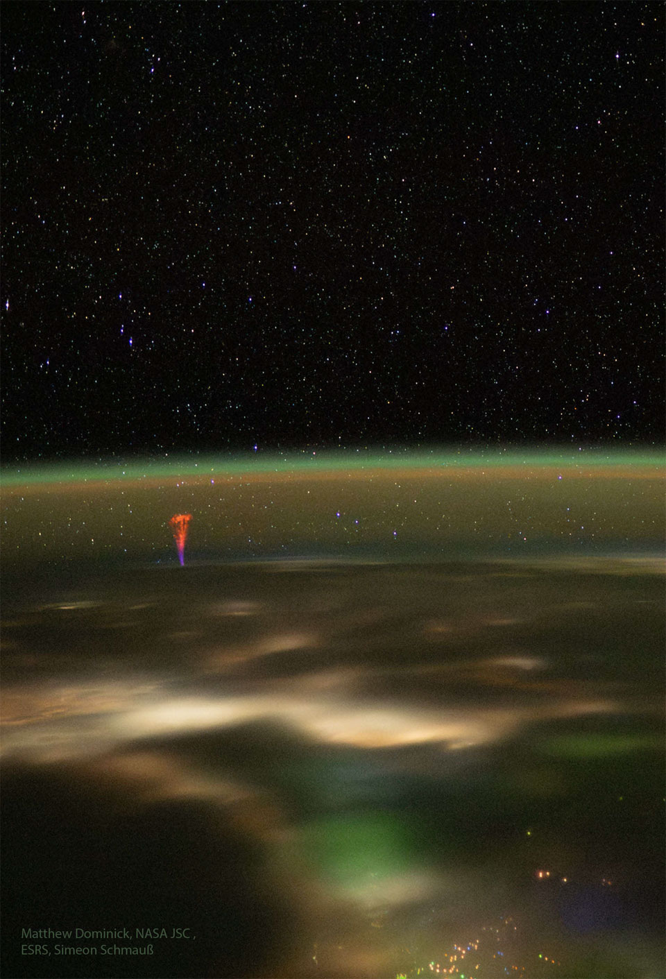 The edge of the Earth is seen from space at night.
The curving horizon is tinted green but a red and blue
jet rises from left. 
Please see the explanation for more detailed information.