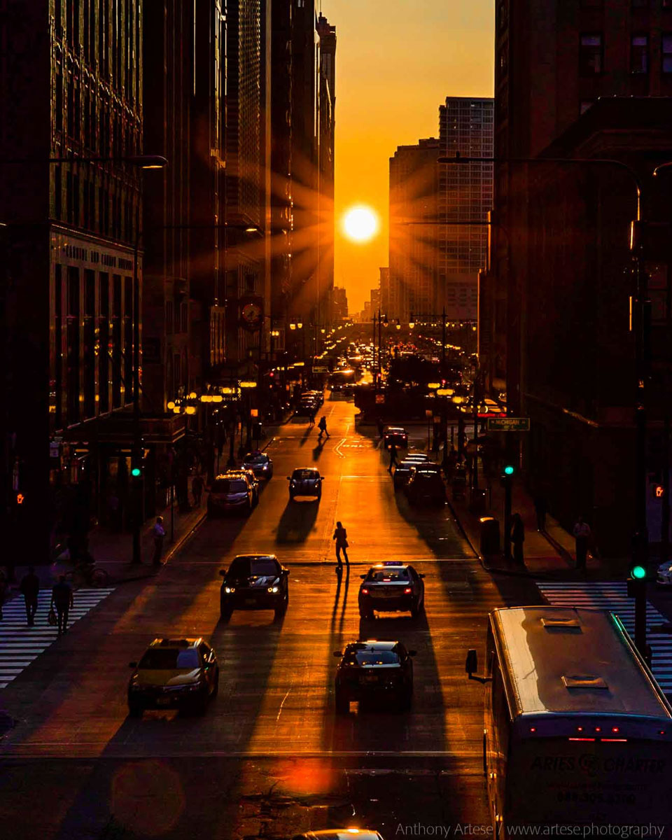 A picture of the Sun setting at the end of a long  city street is shown.   Please see the explanation for more detailed information.