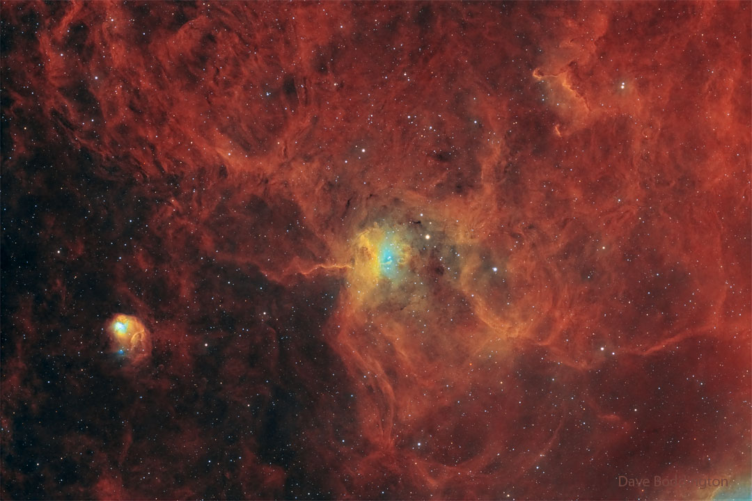 A star field has a red diffuse glow on the right-hand side.
Distinct nebulas appear in the center and on the lower left. 
Please see the explanation for more detailed information.