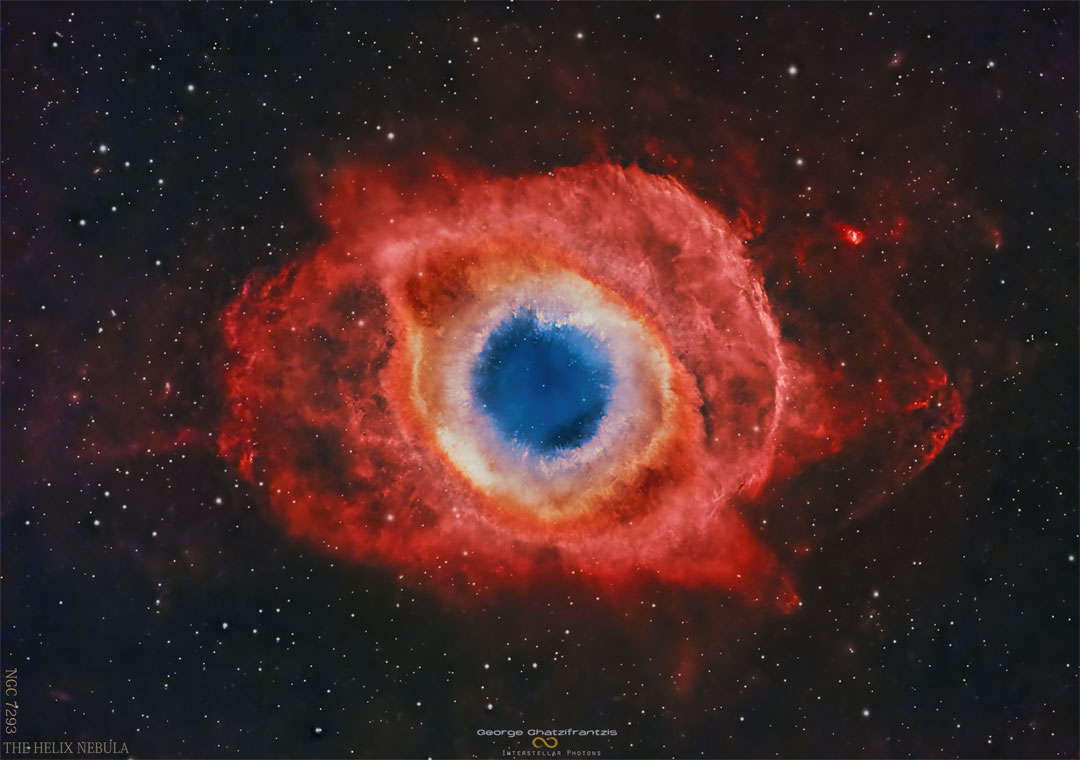 A nearly circular nebula with a blue core 
surrounded by small white knots, an orange ring
and expansive red strucures. 
Please see the explanation for more detailed information.
