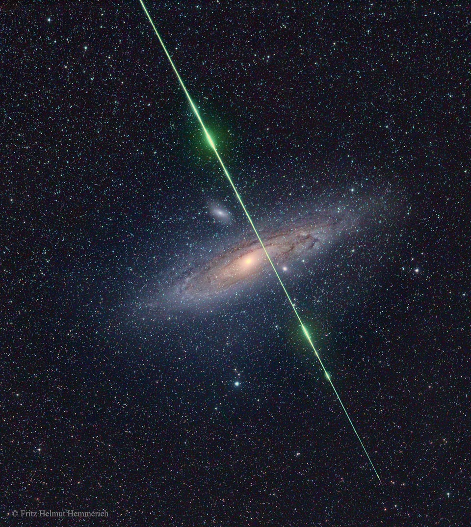 A starfield has the Andromeda galaxy in the center.
Streaking down from the top is a green line with several
bright segments -- a meteor captured coincidently.
Please see the explanation for more detailed information.