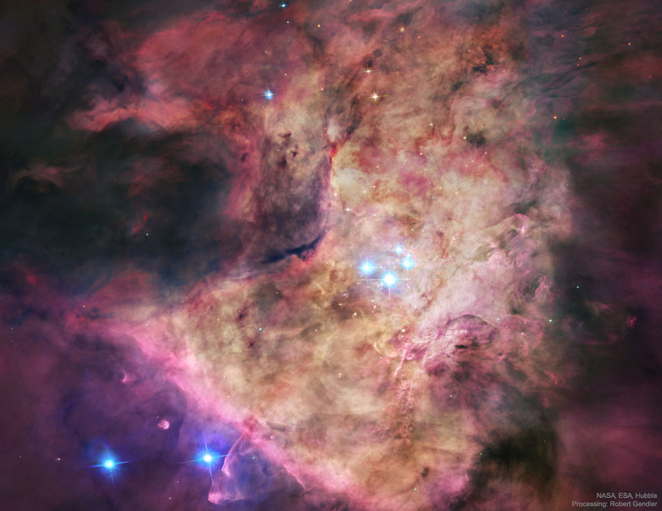 A bright nebula occupies the center of the frame. 
The nebula is complex but roughly tan in the center and
red around the edges. In the center are four bright blue stars.
Please see the explanation for more detailed information.
