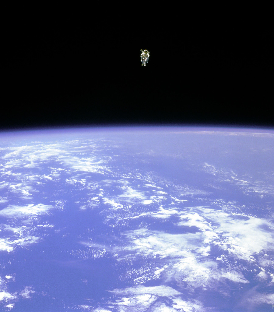 An astronaut is seen hovering over the Earth. In the 
top part of the image, the astronaut is seen against the 
darkness of space. In the lower part of the image, the
Earth is bright blue with white clouds.
Please see the explanation for more detailed information.