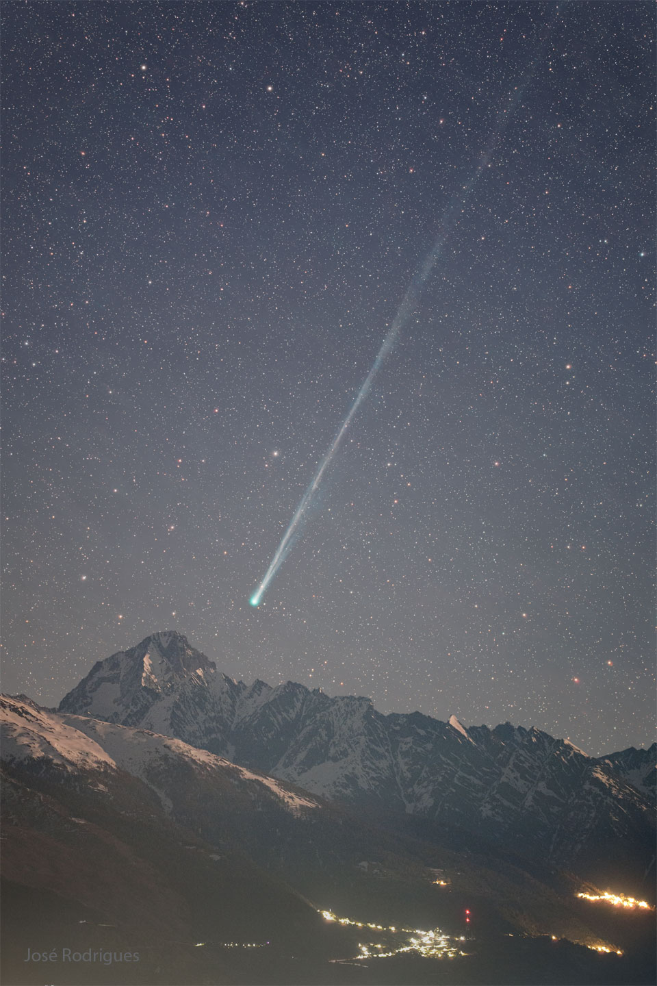 A starry night is seen above foreground mountains. Toward
 the right is a comet with its head near the bottom center
and a long tail extending toward the upper right. 
Please see the explanation for more detailed information.